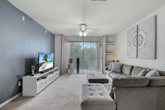 a living room with furniture a flat screen tv and a floor to ceiling window
