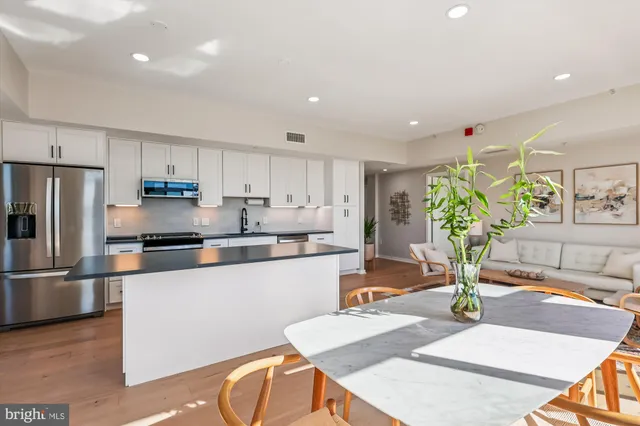 a large white kitchen with granite countertop a large window and stainless steel appliances