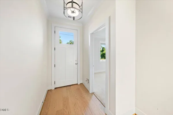 a view of a hallway with wooden floor and a bathroom