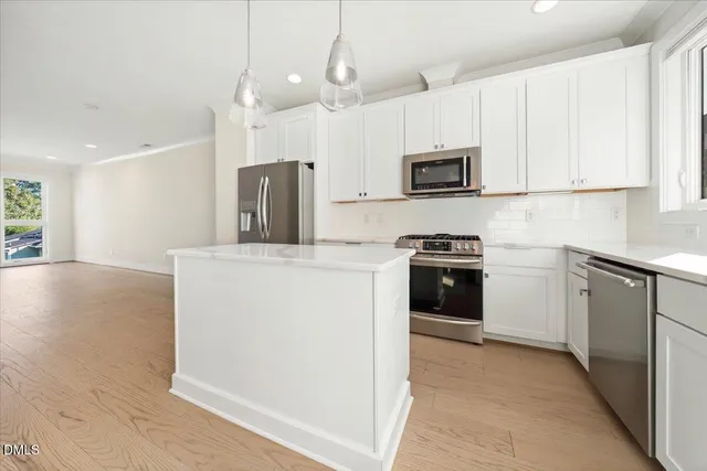 a kitchen with stainless steel appliances white cabinets and wooden floor