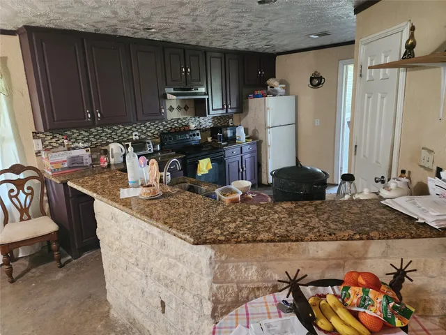 a kitchen with kitchen island granite countertop a sink stove and refrigerator