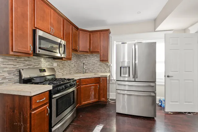 a kitchen with granite countertop wooden cabinets stainless steel appliances and a wooden floor