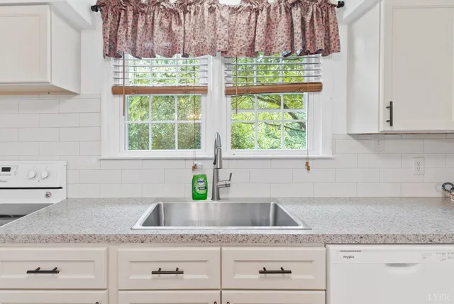 a kitchen with granite countertop a sink a window and cabinets