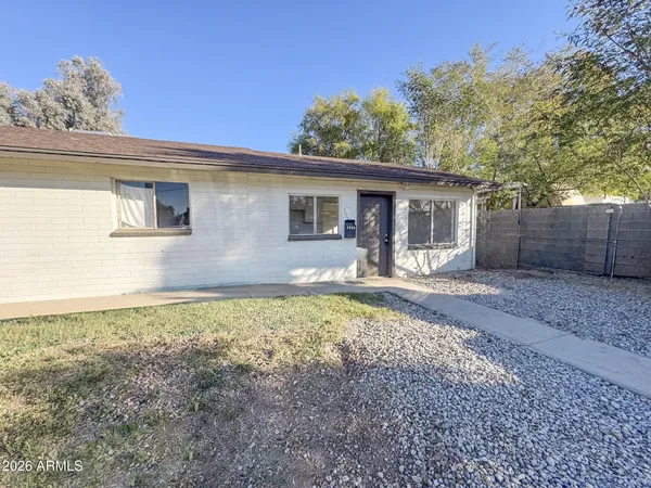 a front view of house with yard and trees in the background