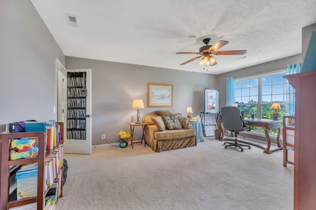 a living room with furniture a ceiling fan and a window