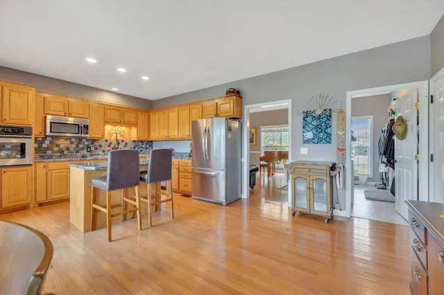 a living room with chairs kitchen view and a large window