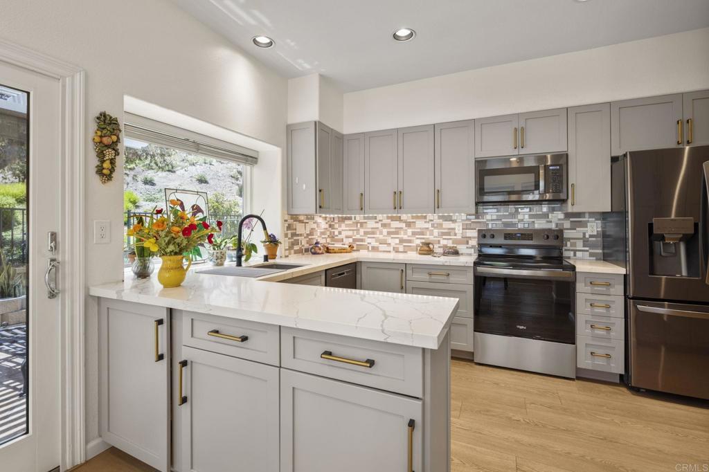 4939 Tilos Way Oceanside, CA 92056 - Photo 16 of 49 a kitchen with stainless steel appliances white cabinets and wooden floor