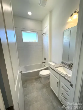 a bathroom with a granite countertop toilet a sink and a mirror