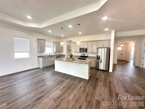 a large kitchen with a center island wooden floor stainless steel appliances and windows