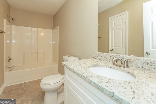a bathroom with a granite countertop sink a toilet and shower