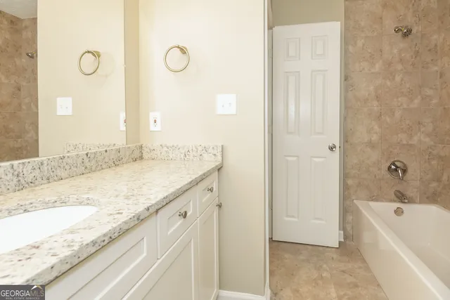 a spacious bathroom with a granite countertop sink and a mirror