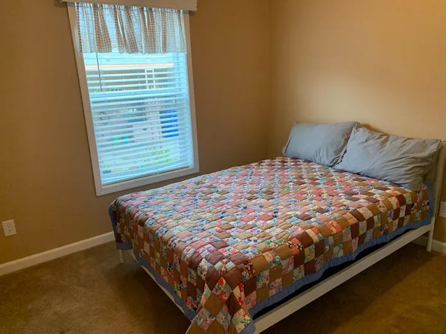 a bed sitting in a bedroom next to a window