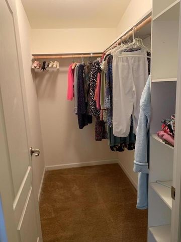 a view of walk in closet with clothes and shoes