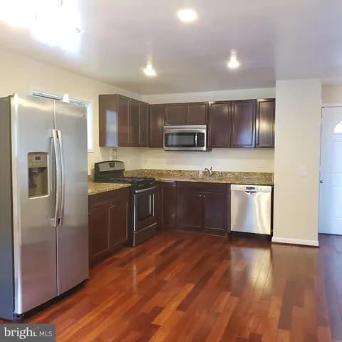 a kitchen with stainless steel appliances granite countertop a stove a sink dishwasher a refrigerator and a oven with wooden floors