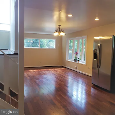 an empty room with wooden floor mirror and windows