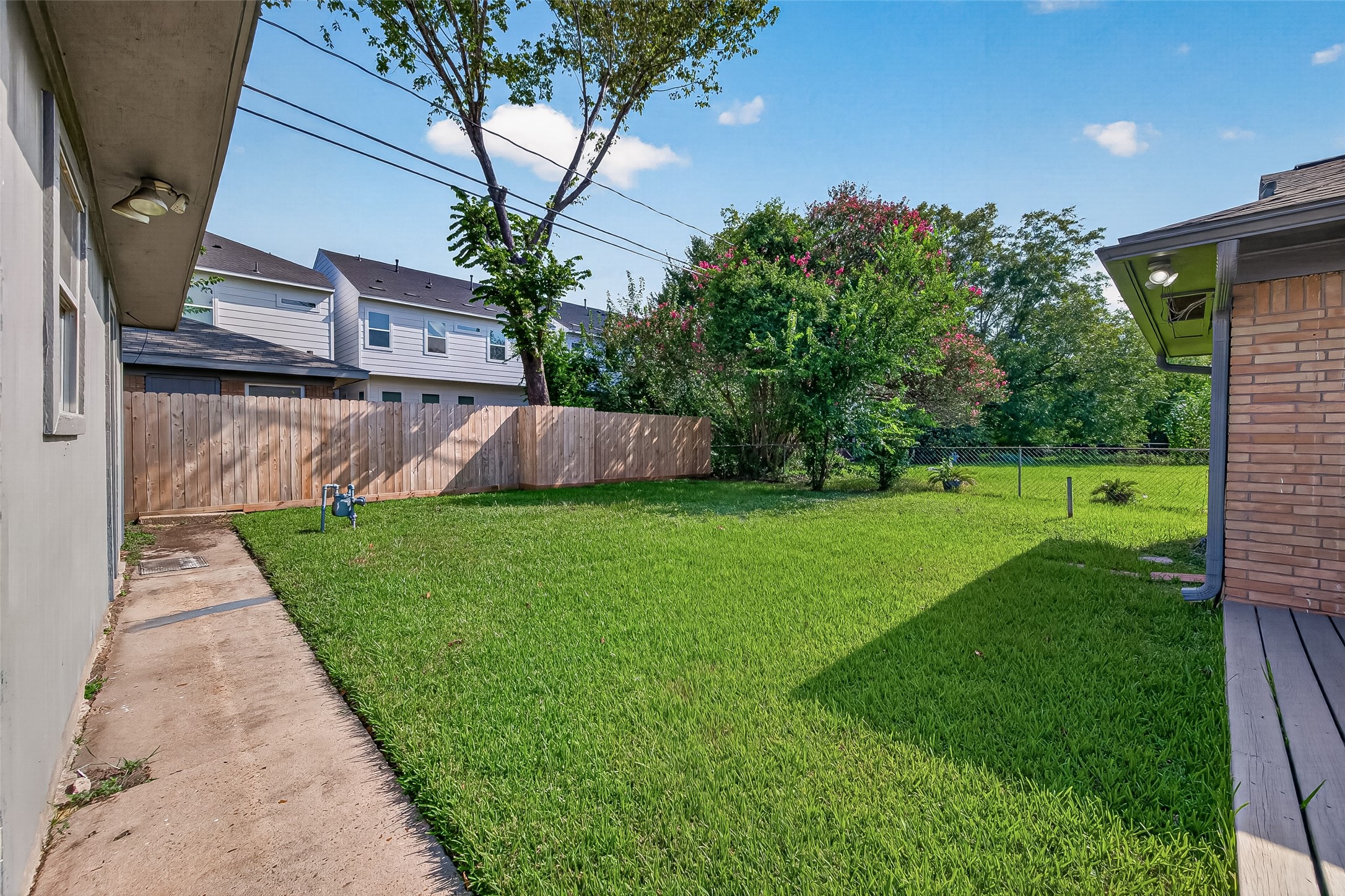 103 East Janisch Road Houston, TX 77022 - Photo 14 of 27 Spacious backyard with well-maintained lawn, privacy fence, and mature trees, perfect for outdoor activities and relaxation.