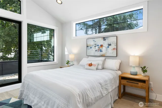 a bedroom with a bed painting on wall and a large window