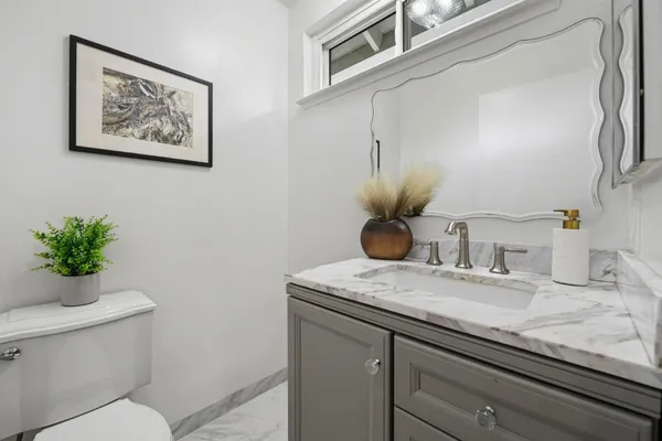 a bathroom with a granite countertop toilet sink and mirror
