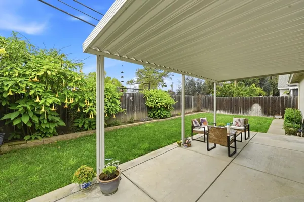 a view of a chair and table in backyard of the house