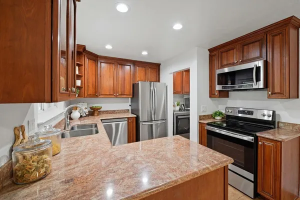 a kitchen with kitchen island granite countertop stainless steel appliances a stove sink microwave and refrigerator