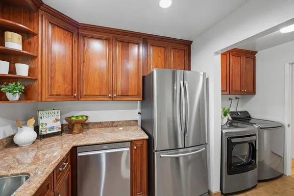 a kitchen with granite countertop stainless steel appliances a refrigerator a sink and cabinets