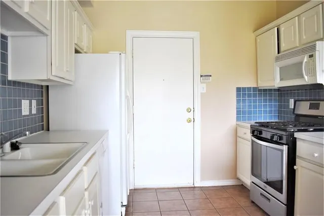 a kitchen with granite countertop a sink stove and refrigerator