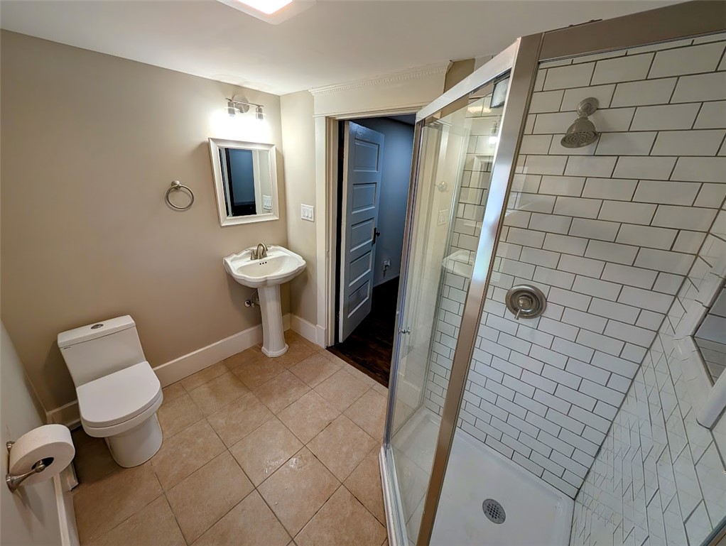 10796 Preble County Line Road Brookville, OH 45309 - Photo 19 of 33 This bathroom features a contemporary shower with subway tile, a pedestal sink, and durable tile flooring.