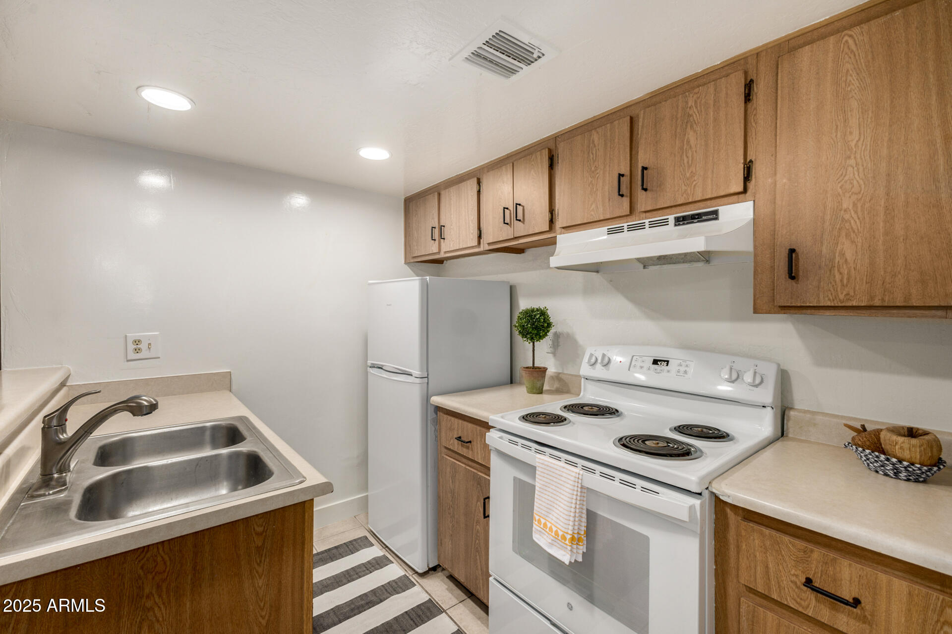 12123 West Bell Road, Unit 110 Surprise, AZ 85378 - Photo 11 of 27 a kitchen with kitchen island a stove a sink and a refrigerator