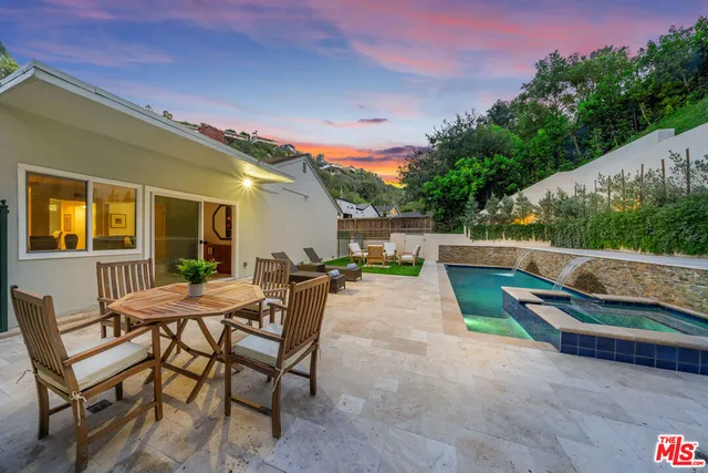 a view of a backyard with couches table and chairs under an umbrella