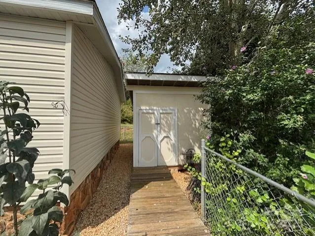 a view of a white house with large trees and wooden fence