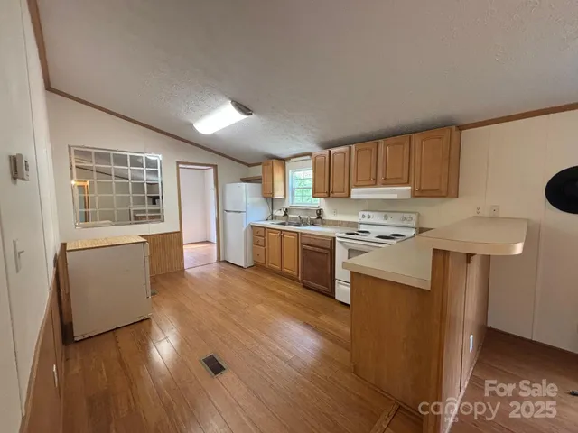 a kitchen with stainless steel appliances granite countertop a stove a sink dishwasher and a refrigerator with wooden floor