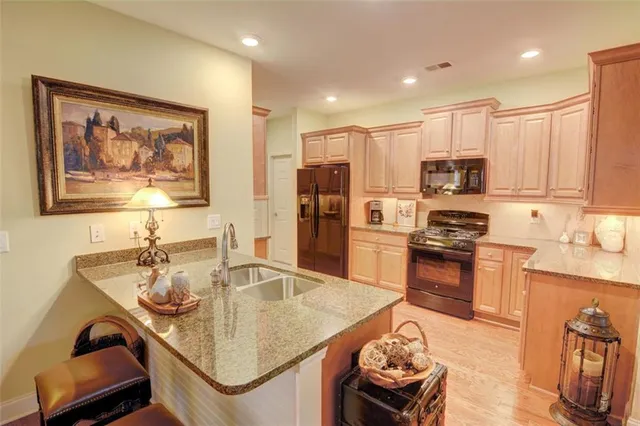 a kitchen with stainless steel appliances granite countertop a stove refrigerator a sink and chairs