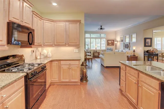 a kitchen with stainless steel appliances granite countertop a stove top oven a sink a dining table and chairs with wooden floor