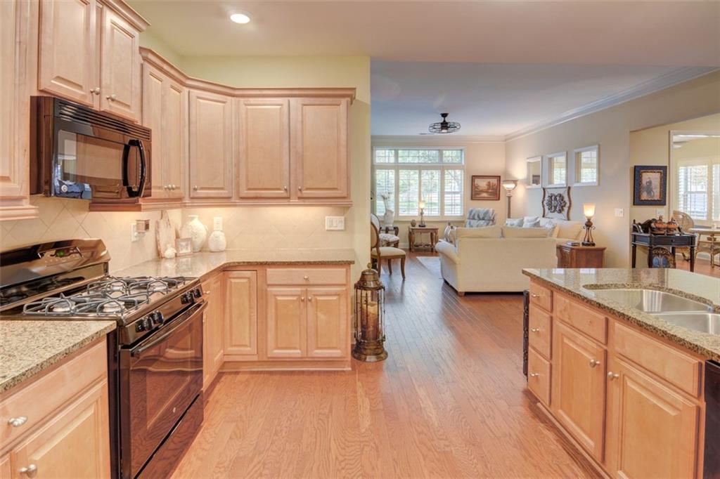 910 Brook Knoll Lane Cumming, GA 30041 - Photo 20 of 36 a kitchen with stainless steel appliances granite countertop a stove top oven a sink a dining table and chairs with wooden floor