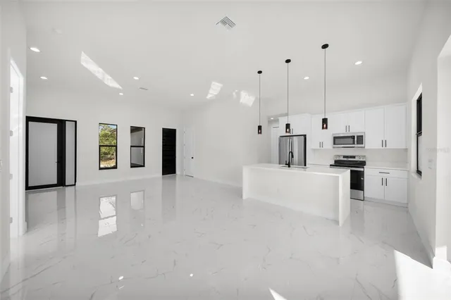 a view of kitchen with kitchen island stainless steel appliances refrigerator stove microwave and cabinets