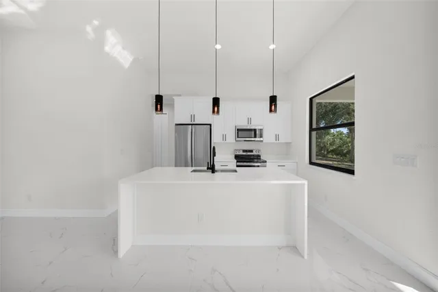 a white kitchen with a sink a window and stainless steel appliances