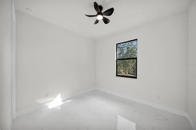 an empty room with a window and a fan