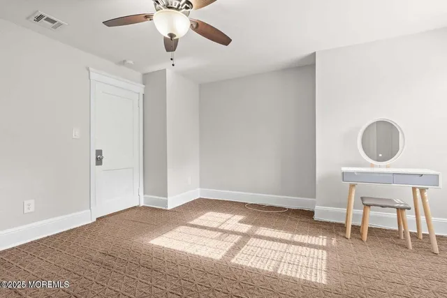 a view of an empty room with wooden floor and a chandelier fan