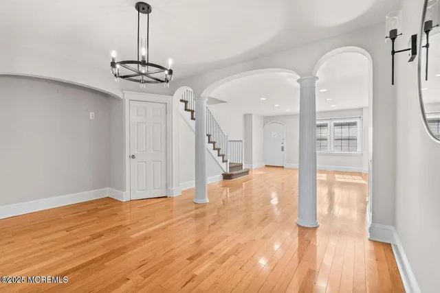 a view of a room with wooden floor a ceiling fan and kitchen view