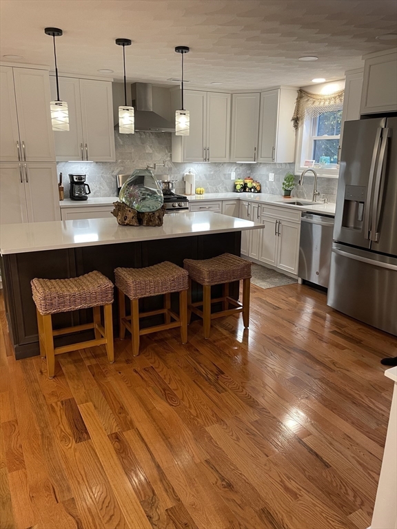 13 High Street, Unit 2 Amesbury, MA 01913 - Photo 7 of 16 a kitchen with stainless steel appliances granite countertop a stove a refrigerator a sink a dining table and chairs with wooden floor