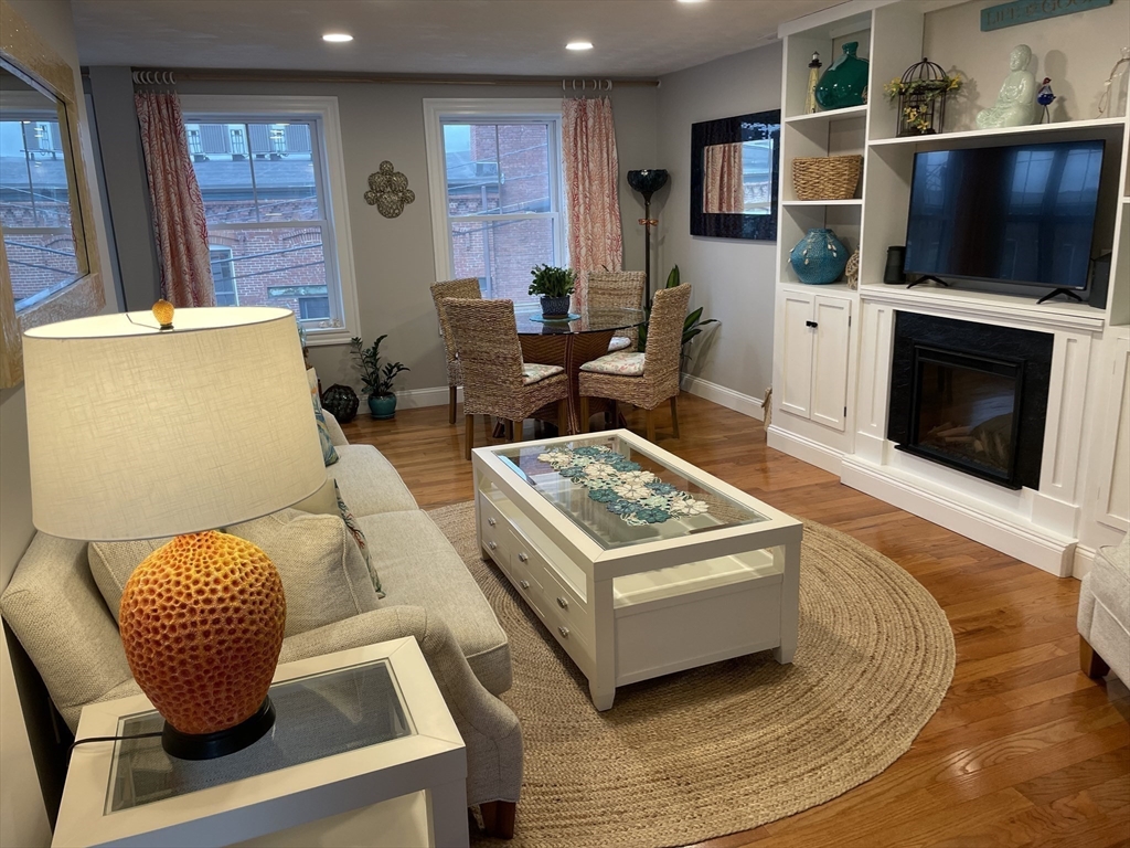 13 High Street, Unit 2 Amesbury, MA 01913 - Photo 8 of 16 a living room with furniture a flat screen tv and a fireplace