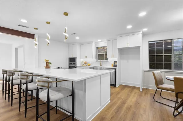a kitchen with a table chairs wooden floors and a view of living room