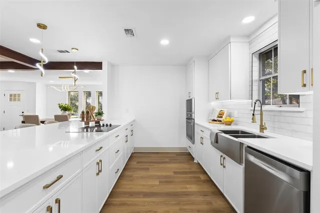 a large white kitchen with lots of counter space and wooden floor