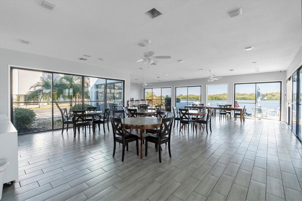 1 Windrush Boulevard, Unit 87 Indian Rocks Beach, FL 33785 - Photo 44 of 54 a dining room with furniture floor to ceiling windows and wooden floor