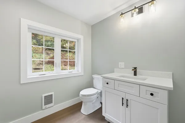 a bathroom with a toilet a sink a mirror and a window