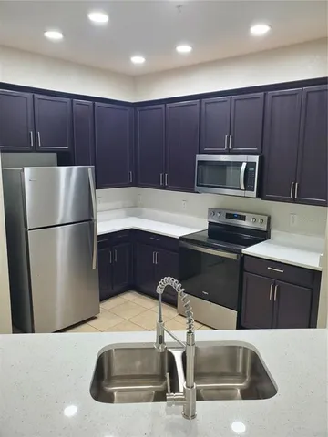 a kitchen with a sink a microwave a refrigerator and cabinets