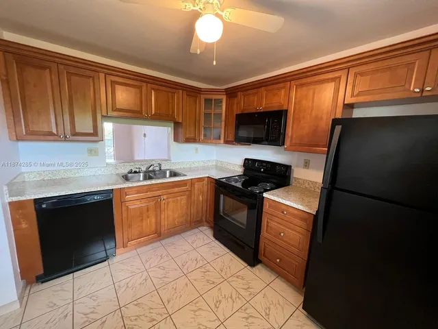a kitchen with granite countertop a refrigerator stove top oven and sink