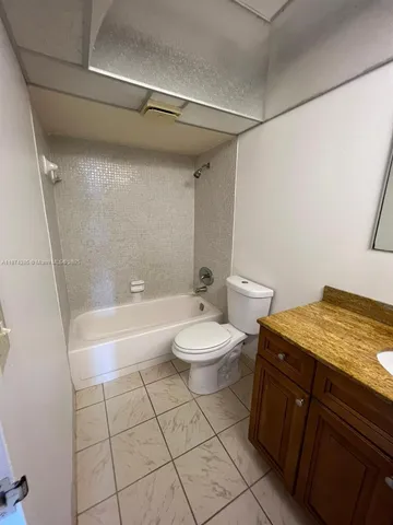 a bathroom with a granite countertop sink toilet a mirror and bathtub