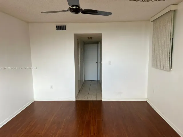 an empty room with wooden floor closet and windows
