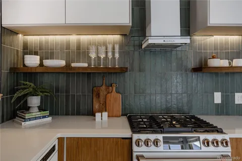 a kitchen with granite countertop a stove a sink and a white wooden cabinets